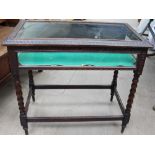 An early 20th century carved bijouterie table with a rectangular glazed top and sides on bobbin