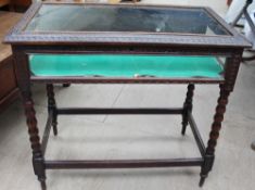 An early 20th century carved bijouterie table with a rectangular glazed top and sides on bobbin