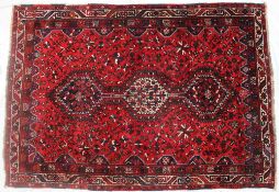 An Iranian wool knotted Kashgai red ground rug with medallions,