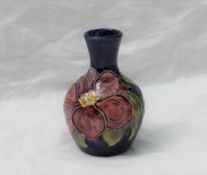 A small Moorcroft pottery vase, decorated in the Clematis pattern to a Royal blue ground,