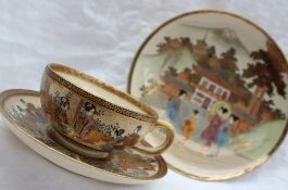 A Japanese satsuma pottery teacup and saucer decorated with figures in interior and exterior