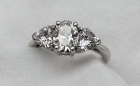 A three stone diamond ring, the central oval brilliant measuring 8.20 x 5.85 x 3.69mm totalling 1.