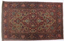 A wool knotted Persian Kashan rug, with a red ground and scrolling flowers and leaves,