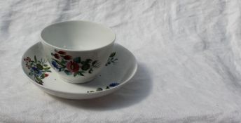 A Newhall porcelain tea bowl and saucer, decorated with sprays of garden flowers,