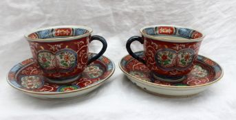 A pair of Japanese porcelain cups and saucers,