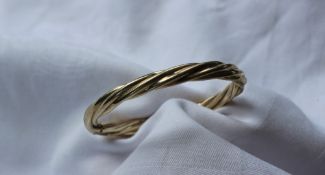 A yellow metal twist hinged bangle,