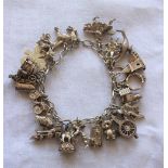 A silver charm bracelet set with numerous charms including a pony, car, shamrock, train, cupid,