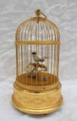 A Sainte-Croix Reuge music automaton of a singing bird on a perch in a domed gilded cage,