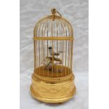 A Sainte-Croix Reuge music automaton of a singing bird on a perch in a domed gilded cage,