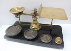 A pair of postal scales and weights, with a wooden base, brass pan and scales,