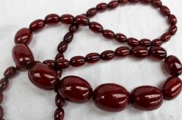 A cherry amber bead necklace with graduated oval beads, 27mm to 10mm,