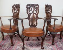 A set of three 19th century mahogany elbow chairs, with a C scrolling and leaf carved pierced back,