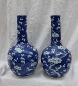 A pair of Chinese prunus blossom bottle vases, with a cylindrical neck and bulbous base,