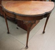A reproduction mahogany half round table on three legs