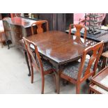 A reproduction mahogany extending dining table with four dining chairs and serpentine fronted