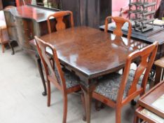 A reproduction mahogany extending dining table with four dining chairs and serpentine fronted