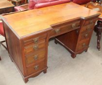 An Edwardian walnut pedestal desk with two banks of four drawers either side of a central drawer