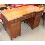 An Edwardian walnut pedestal desk with two banks of four drawers either side of a central drawer