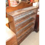 An oak bookcase with a shaped top and four shelves on bracket feet