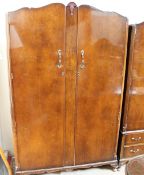 A 20th century walnut bedroom suite comprising two wardrobes and a dressing table together with a