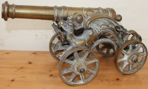 A cast brass model canon with a ring turned barrel with dragon supports and spoke wheels