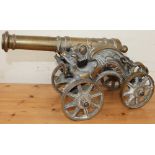 A cast brass model canon with a ring turned barrel with dragon supports and spoke wheels