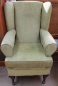 An upholstered wing back elbow chair