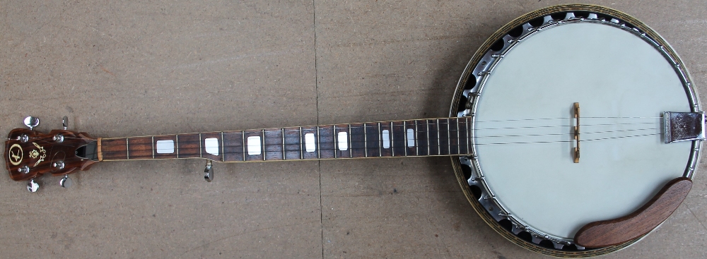 A five string banjo with a silver eagle emblem on the reverse,