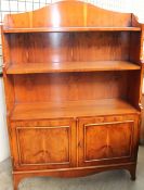A reproduction yew waterfall bookcase with a cupboard base on bracket feet