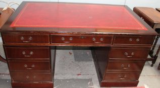 A reproduction mahogany pedestal desk with a leather inset top on plinths
