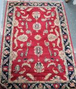 A small Persian red ground rug with floral swags