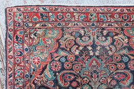 A Persian Mahal rug with a red ground and central blue medallion and flowers
