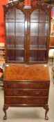 A 20th century walnut bureau bookcase on leaf carved cabriole legs and books