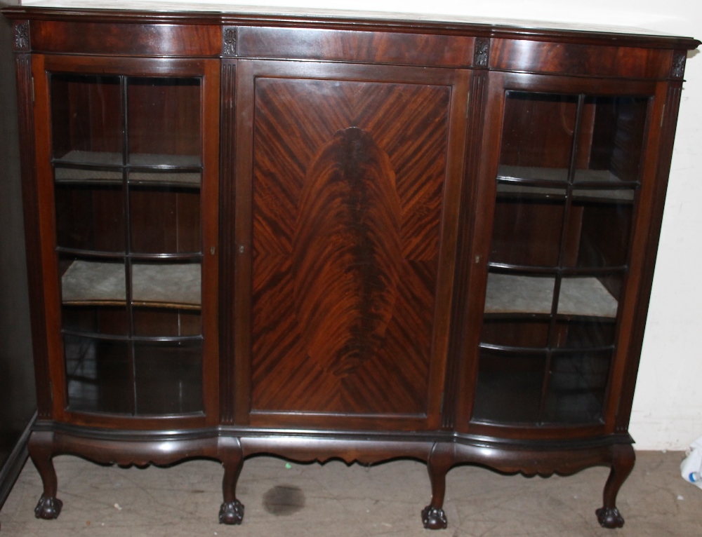 An Edwardian mahogany bookcase, the shaped top above a central door, the sides with glazed panels,