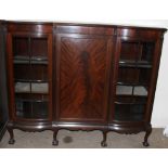 An Edwardian mahogany bookcase, the shaped top above a central door, the sides with glazed panels,