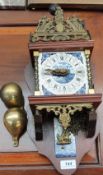 A modern wall clock with brass weights and blue and white tiles