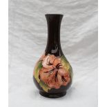 A Moorcroft pottery single stem vase painted with poppies to a brown ground 16cm high