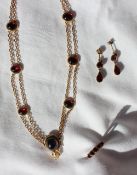A yellow metal and garnet set necklace,