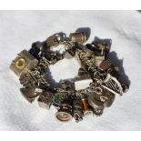 A white metal charm bracelet set with numerous white metal charms including cottages, teddy bear,