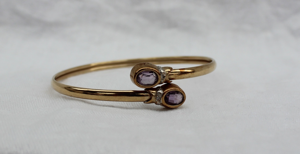 A 9ct yellow gold bangle, set with two oval faceted amethysts, - Image 2 of 3