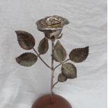 An Elizabeth II Silver rose, with leaves on a stem mounted in a wooden domed base, London, 1965, 31.