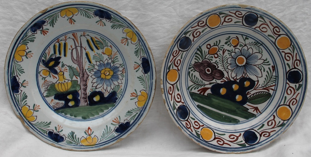 A Delft polychrome plate, decorated with a vase of flowers, trees, with a floral border, 23.