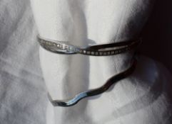 A 9ct white gold hinged bangle of wave form, together with a paste set 9ct white gold hinged bangle,