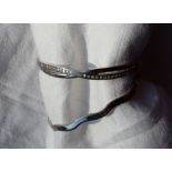 A 9ct white gold hinged bangle of wave form, together with a paste set 9ct white gold hinged bangle,