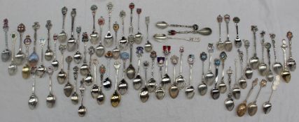A large collection of white metal and enamel decorated souvenir spoons