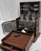 An early 20th century oak liquor cabinet, the hinged front enclosing a tray, three decanters,