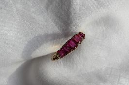 An 18ct yellow gold five stone ruby line ring, set with a central ruby at 5.4 x 4.8mm, two at 5.