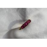 An 18ct yellow gold five stone ruby line ring, set with a central ruby at 5.4 x 4.8mm, two at 5.