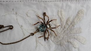 A yellow metal spider brooch, with an aquamarine coloured body,
