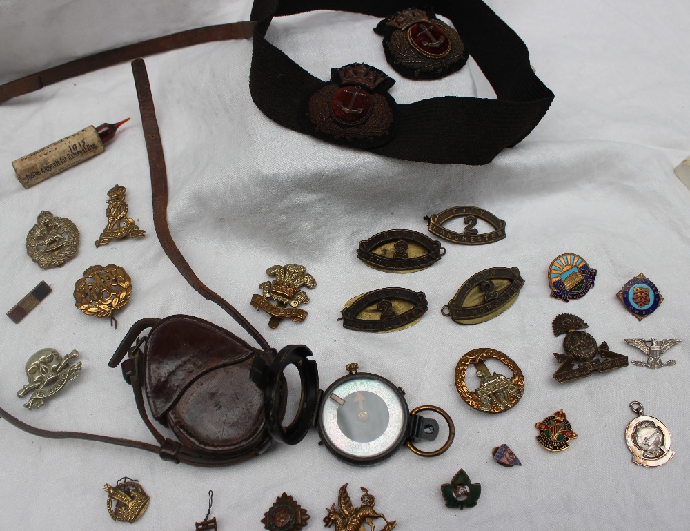 A World War I Vernier's pattern VII compass, together with cap badges,